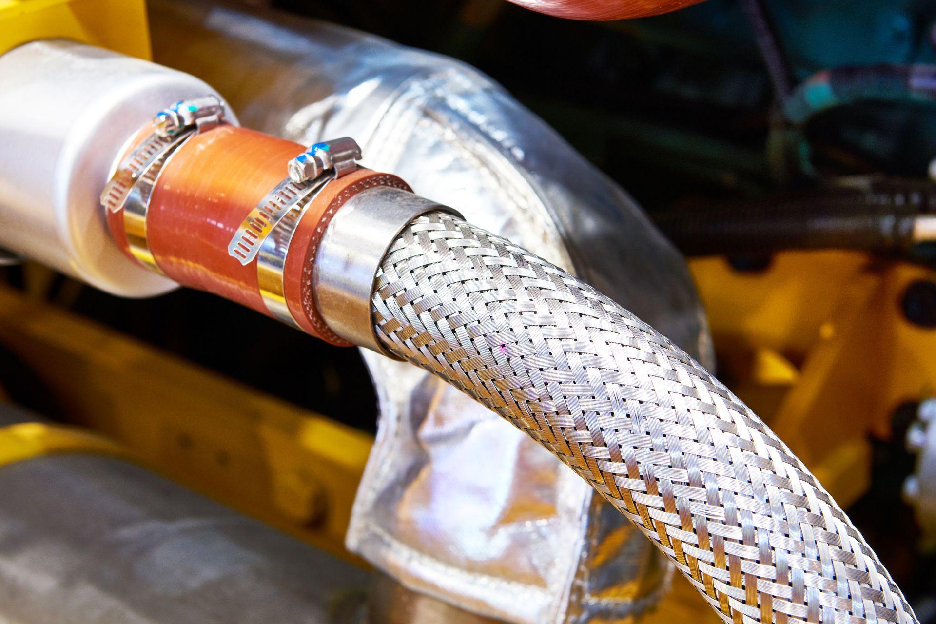 Detailaufnahme einer Schlauchklemme aus Edelstahl an einem Metallschlauch im Industrieeinsatz – Beispiel für professionelle und dichte Verbindung