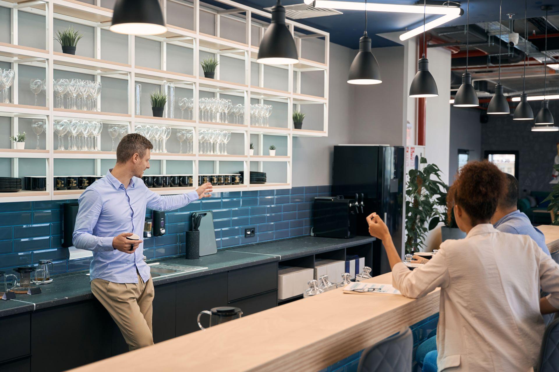 Mitarbeiter in moderner Büroküche mit energieeffizientem Getränkekühlschrank